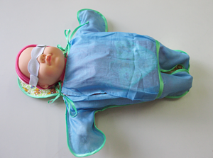 Новорожденный во фланелевом конверте с полупрозрачными для синего света окнами со стороны спины и груди.